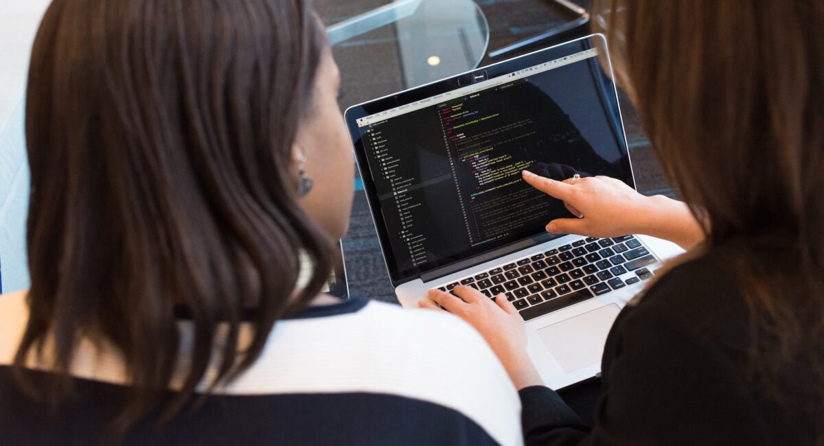 woman using MacBook Pro with person in white top