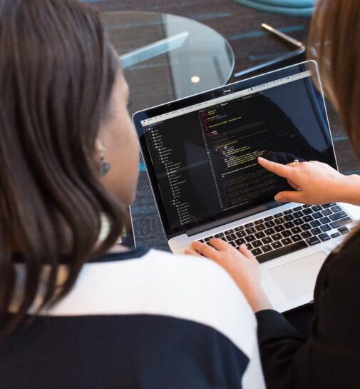 woman using MacBook Pro with person in white top