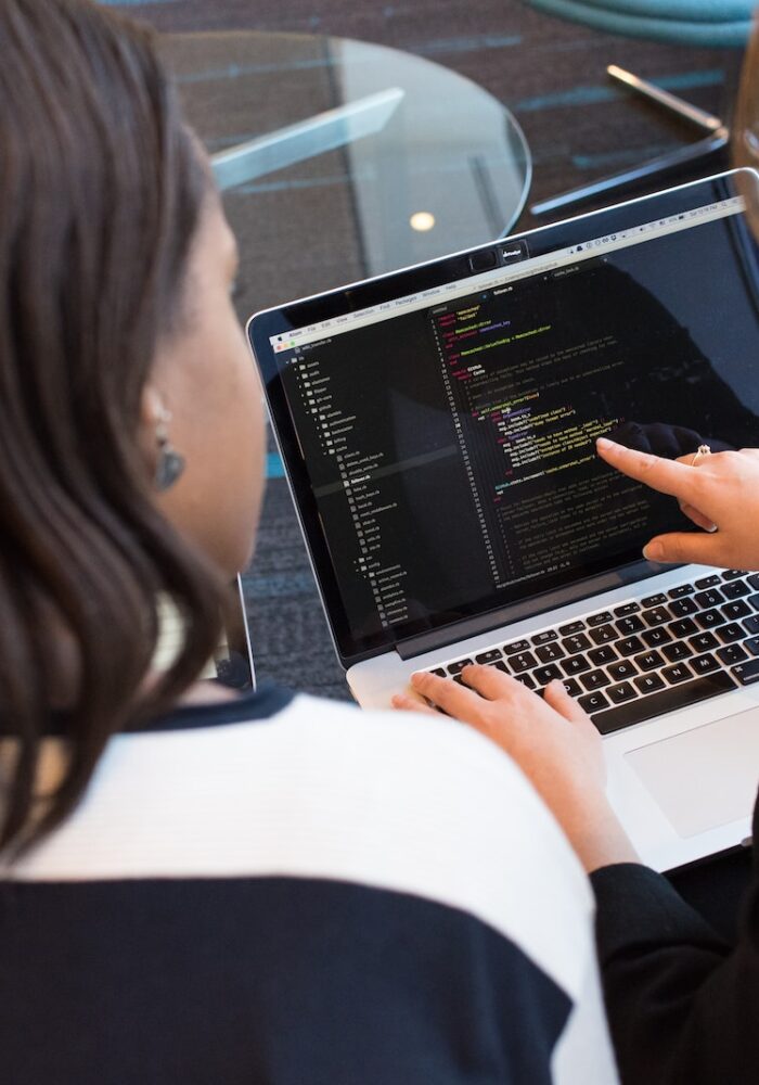 woman using MacBook Pro with person in white top